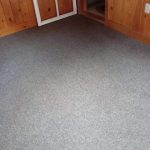 grey carpeted floor with stains removed after cleaning with wood panel walls